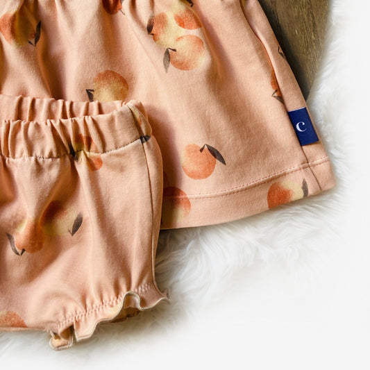 Detail van het Jurkje Peach met bijpassende bloomer, handgemaakt en zacht voor baby's huid. Trendy en duurzaam babysetje voor zomerse dagen.