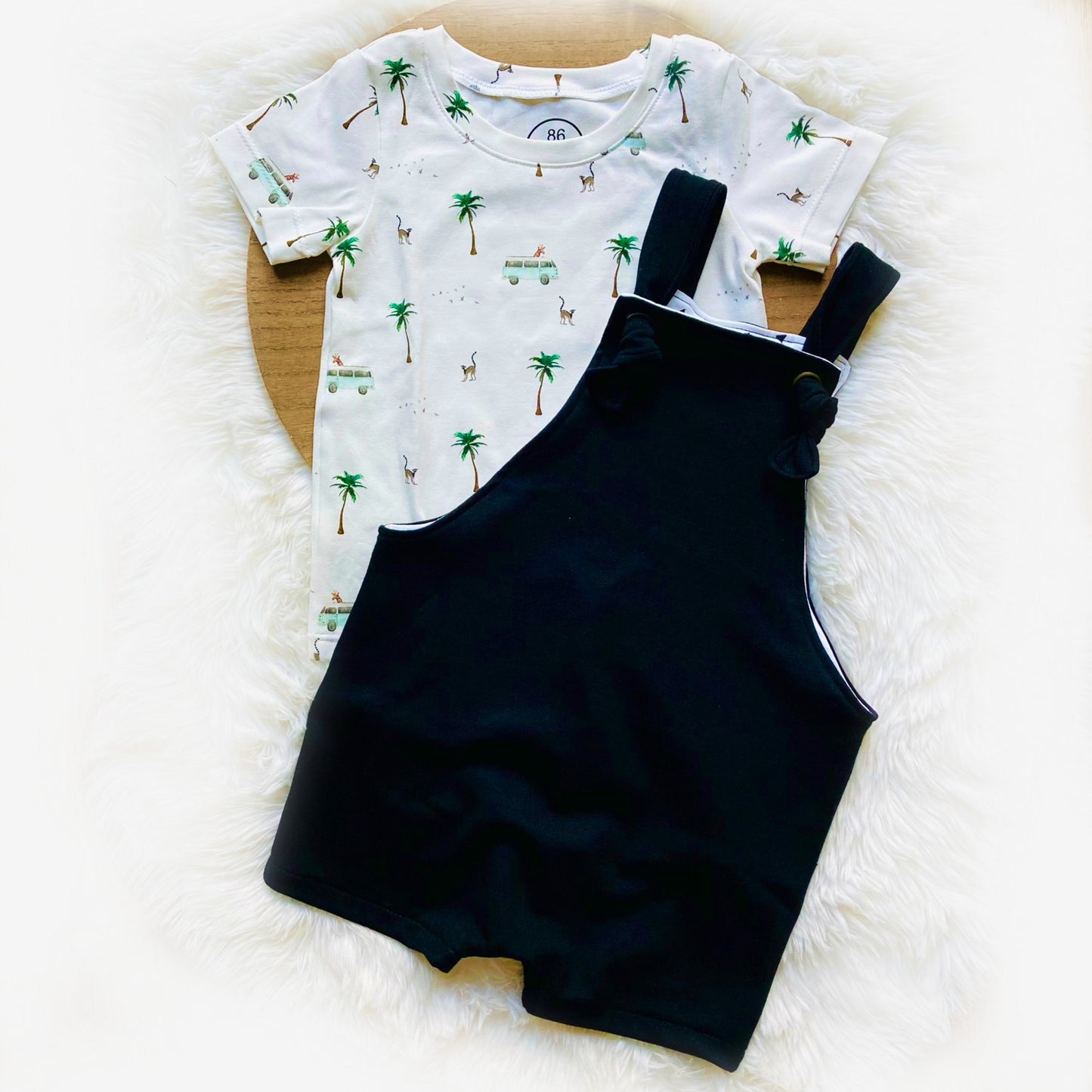 Zwarte knotted overall tuinbroek met een zomers T-shirt met safari-print. Perfecte outfit voor baby's en kinderen in maat 50-122.