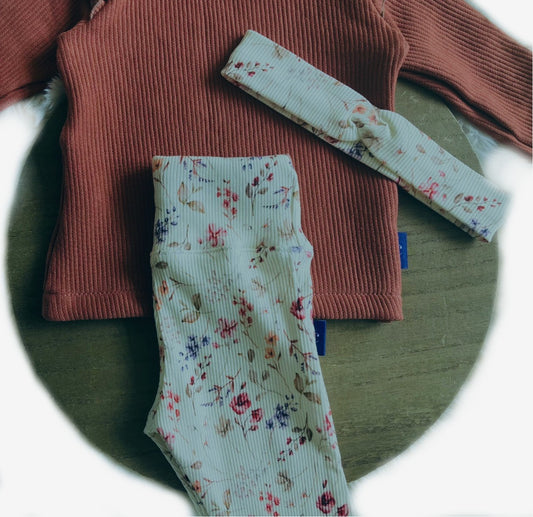 Detail van flare broek & haarband Rosie, bloemenprint op ribtricot stof, gecombineerd met een roestkleurige top met ruches.