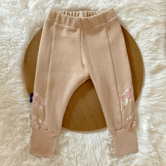Sfeerfoto van schattige handgemaakte babykleding in zachte tinten, verkrijgbaar bij Cuteez - jouw bestemming voor duurzame kinderkleding online. 