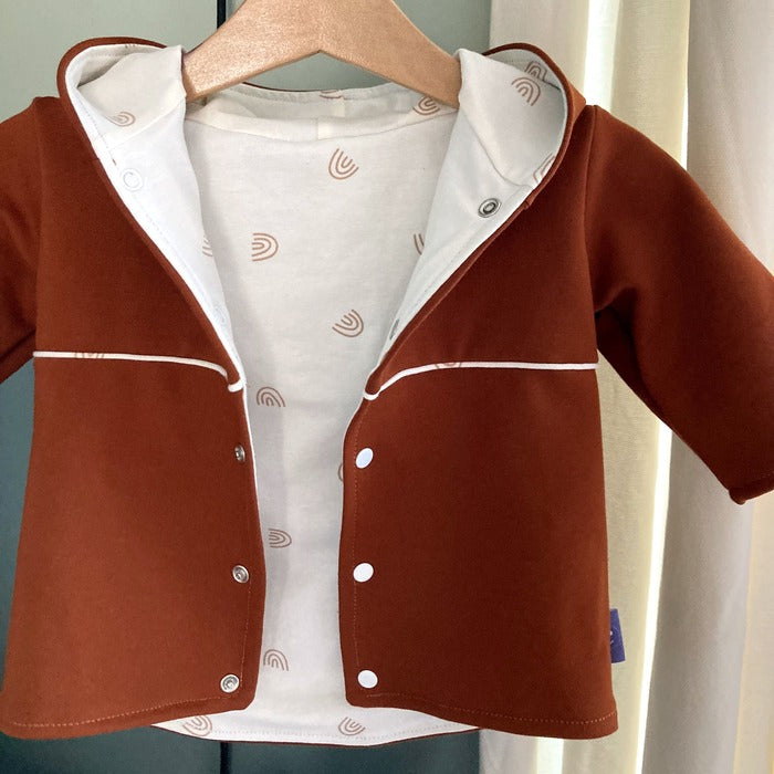 Sfeerfoto en detail van voering van Jasje choco, bruin baby jasje met witte voering, drukknoopjes en capuchon. Handgemaakte duurzame babykleding.  