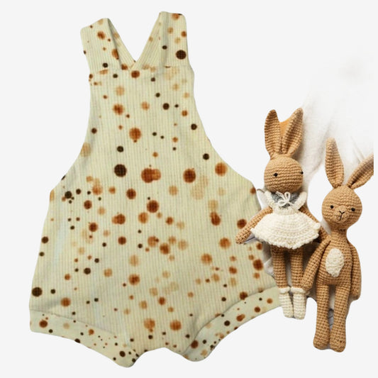 Flatlay van een Cuteez baby overall shortie zomerpakje van offwhite wafelstof met bruine stippel. Handgemaakte babykleding uit collectie van duurzame kinderkleding online webshop. 
