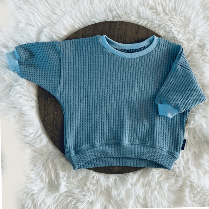 Een close-up van ons zachte blauwe truitje, met liefde handgemaakt voor je kleintje. Ontdek onze collectie handgemaakte kinderkleding en duurzame kinderkleding online op Cuteez