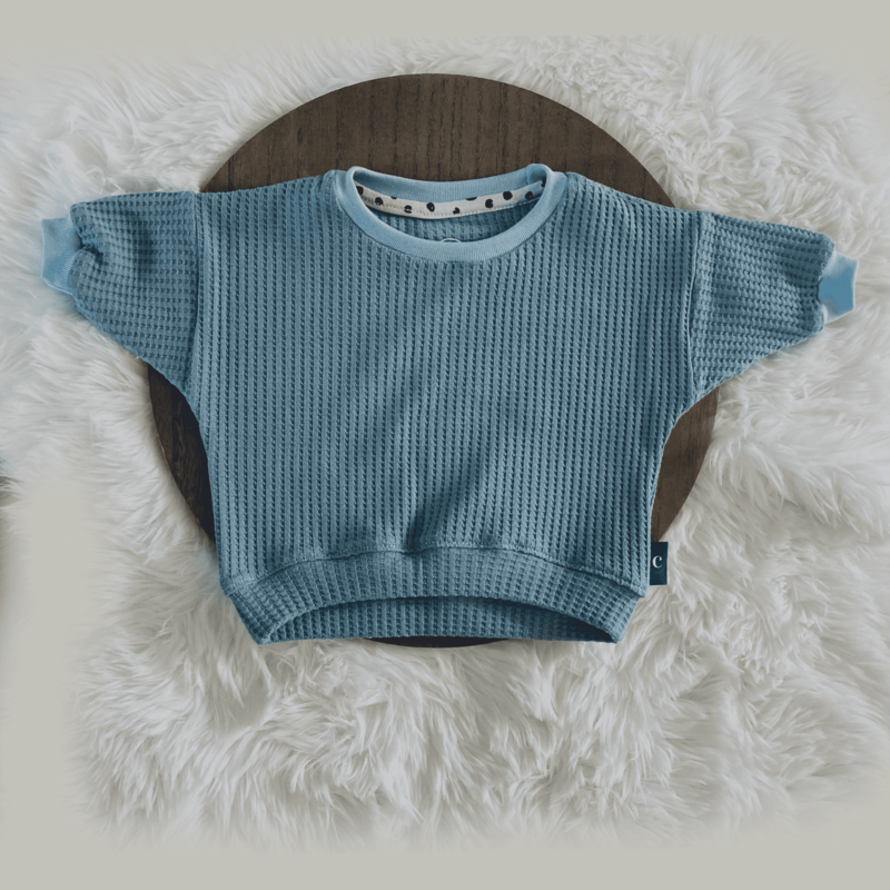 Bekijk deze schattige en zachte sweater van dichtbij. Een pronkstuk uit onze collectie handgemaakte babykleding, beschikbaar in de webshop Cuteez.