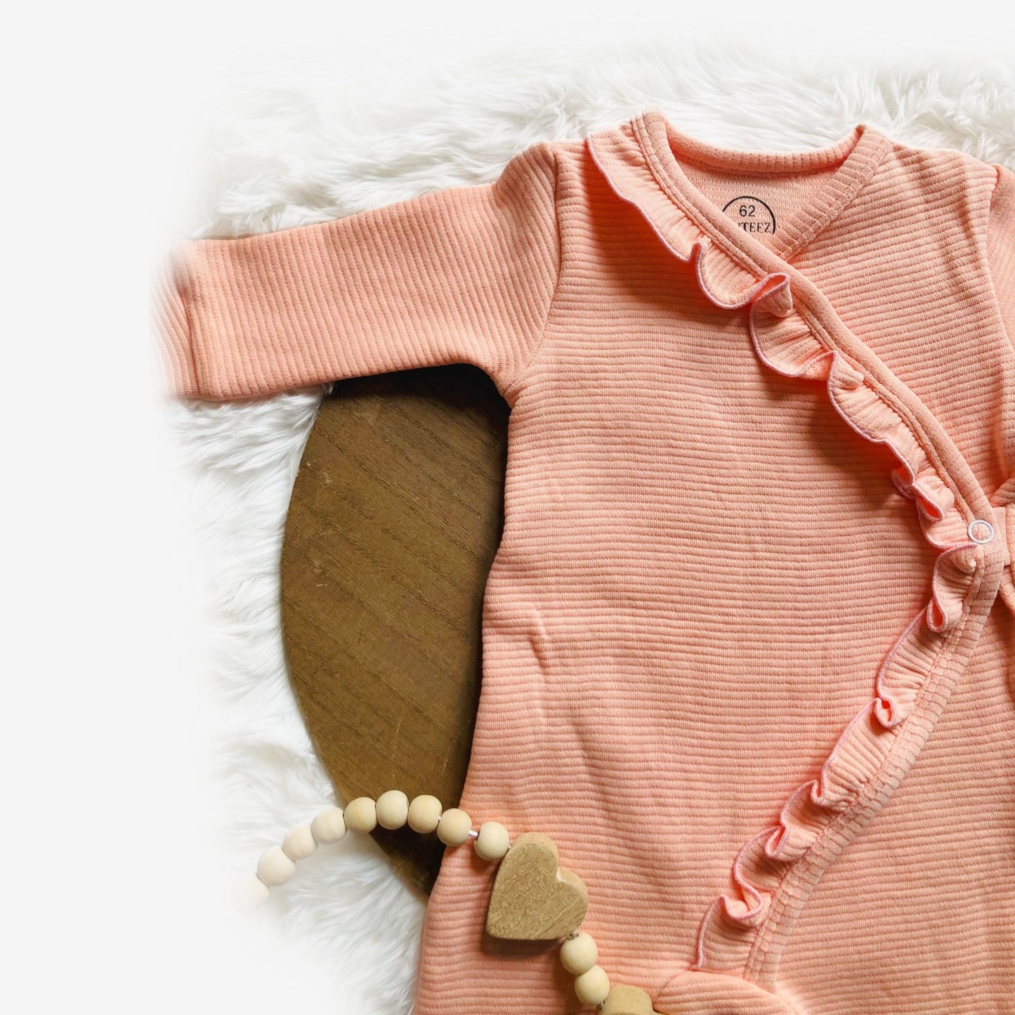 Detail van Heerlijke perzikkleurige overslagromper boxpakje babypakje meisje ruffle. Handgemaakte babykleding van webshop Cuteez. 