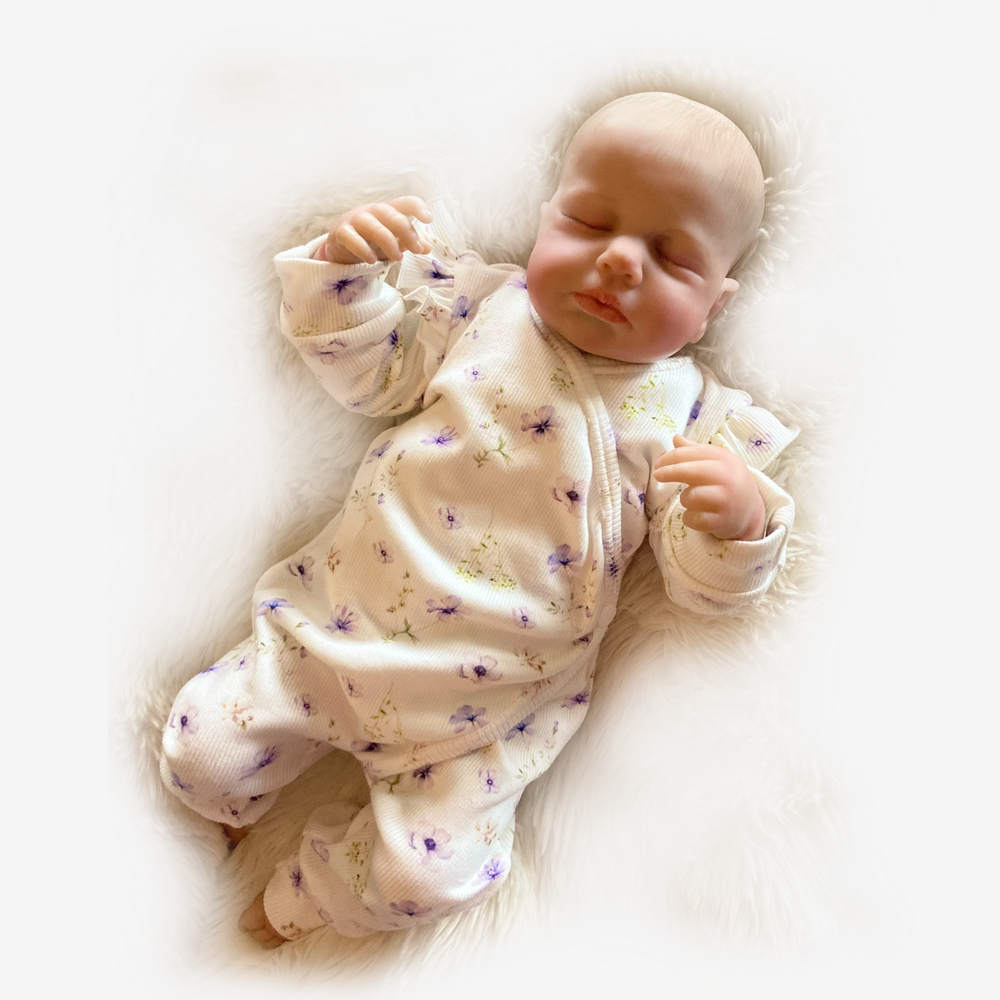 Babymeisje draagt offwhite ribstof boxpakje met blauw-paarse bloemetjes en schouderruffles van Cuteez.