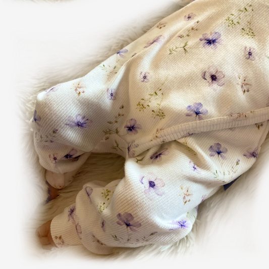 Detail van offwhite ribstof boxpakje met blauw-paarse bloemetjes en schouderruffles van Cuteez.