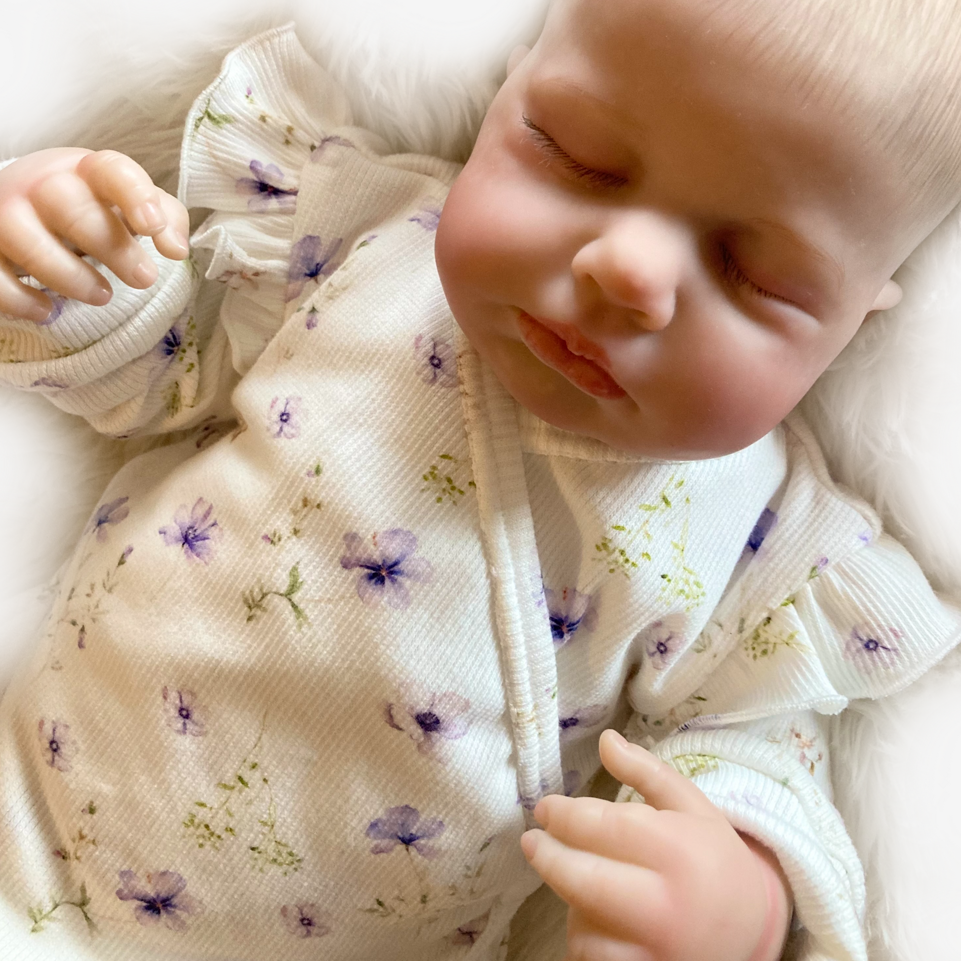 Newborn meisje in zacht rib boxpakje met bloemenprint en ruffles op de schouders, handgemaakt door Cuteez.