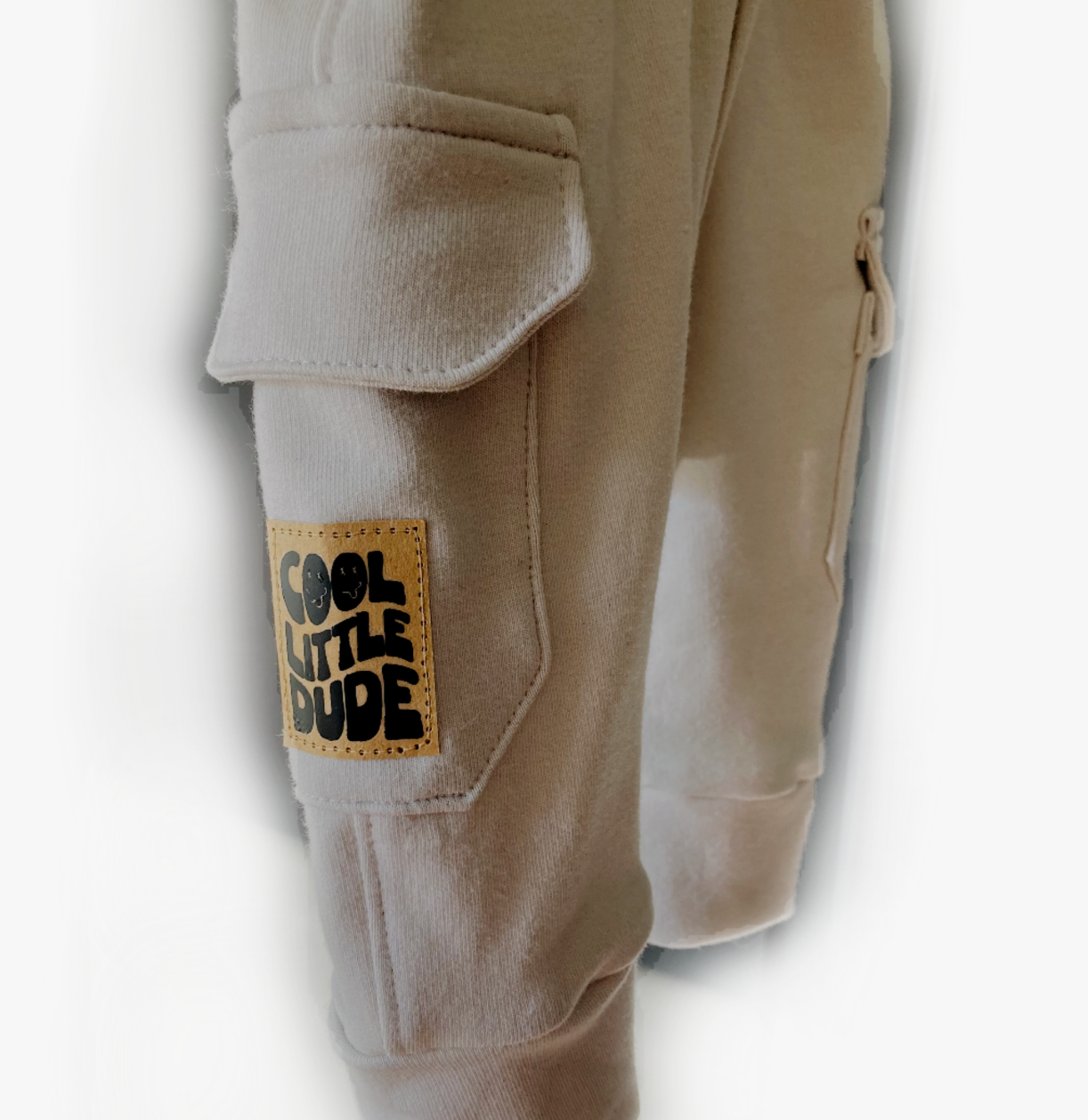 Detail van Cargo broek Grey met stoere zakken en een leren label met de tekst 'Cool Little Dude'. Handgemaakt en duurzaam.