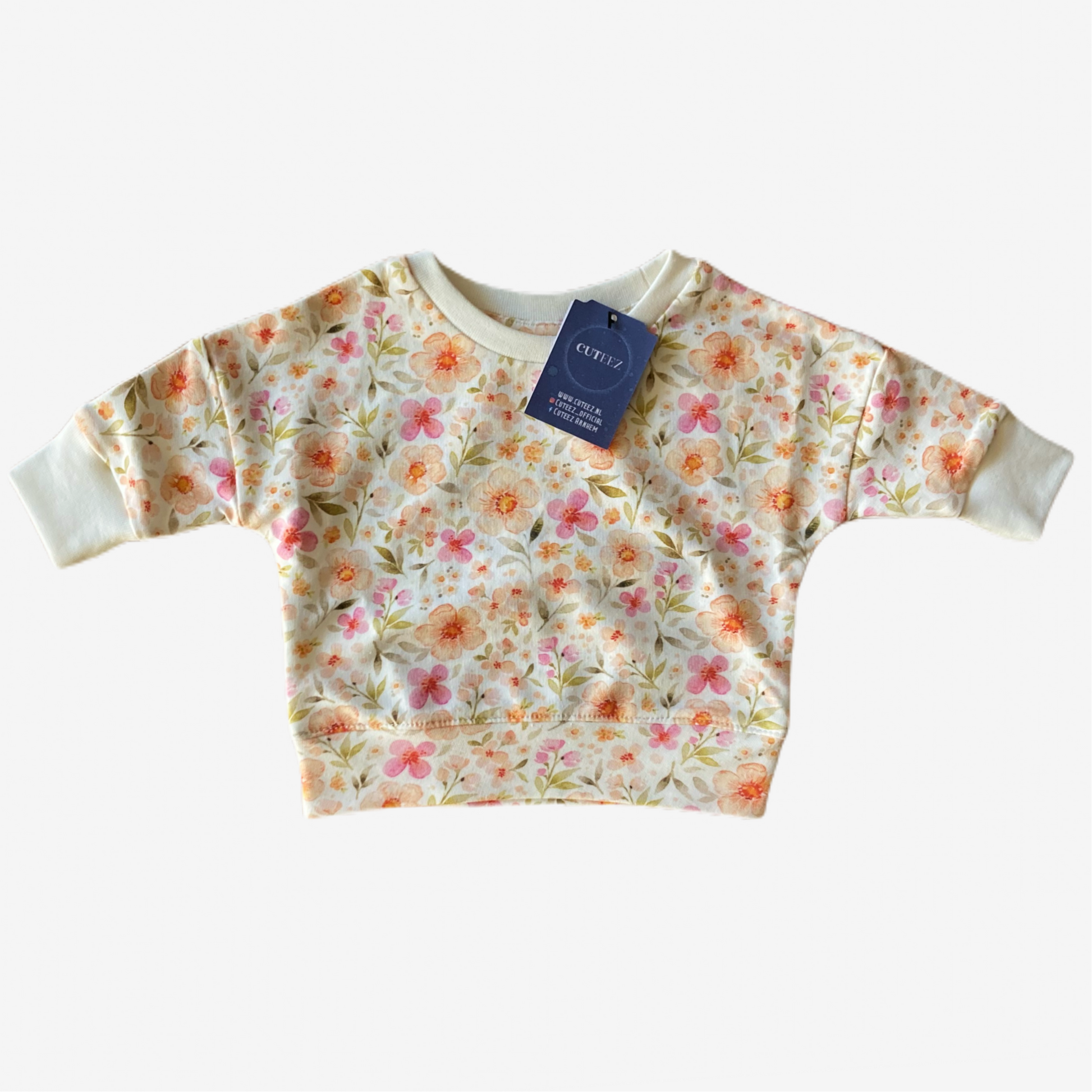 Flatlay van oversized babytrui Amelia met gebloemde print en zachte offwhite boordjes, maat 56-104
