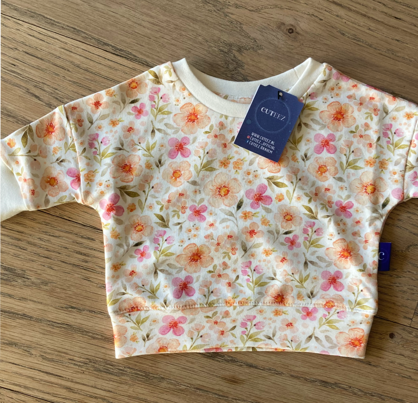 Detailfoto van duurzame, handgemaakte babytrui Amelia in bloemenprint met offwhite boordjes, geschikt voor peuters.